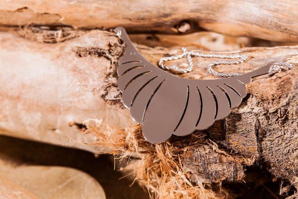 Collana in acciaio a forma di piuma su un ramo di legno di mare