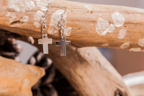Orecchini a forma di croce appesi a un ramo di legno di mare