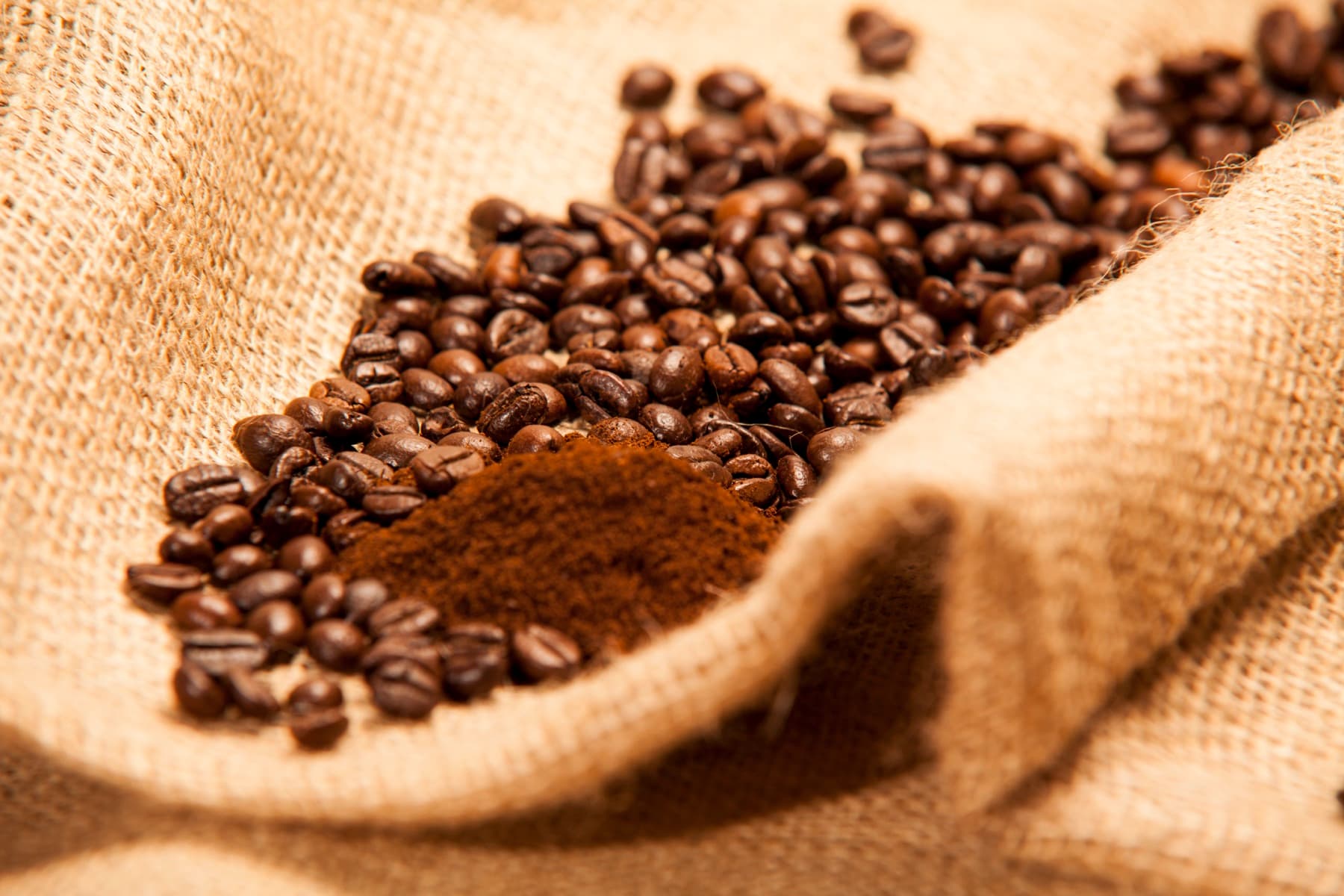 Chicchi e polvere di caffè su una tela di juta